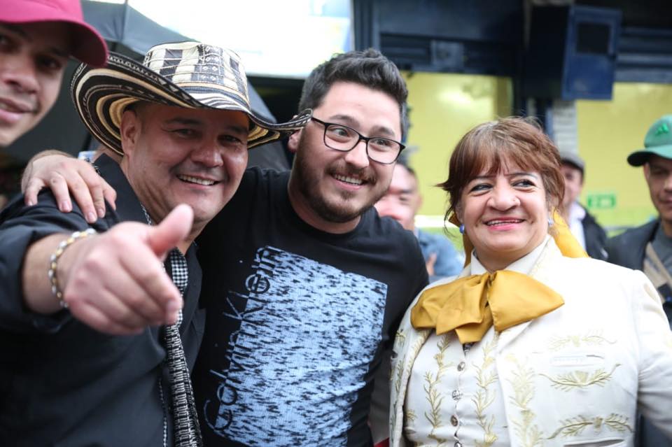 El Señor Edil de la Alcandía, Un representante de los grupos de Vallenato y la Fundadora, se encuentran sonrientes abrazados en una actividad cultural de FUNDAR.