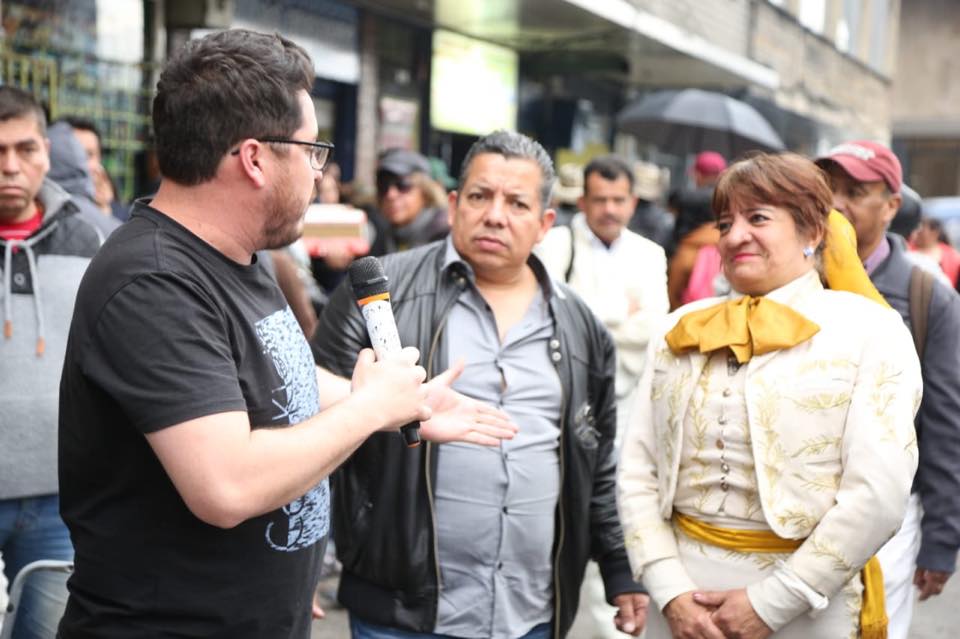 El Edil plantenado y hablando a micrófono, frente a la fundadora con traje charro y varios asistentes alrededor.