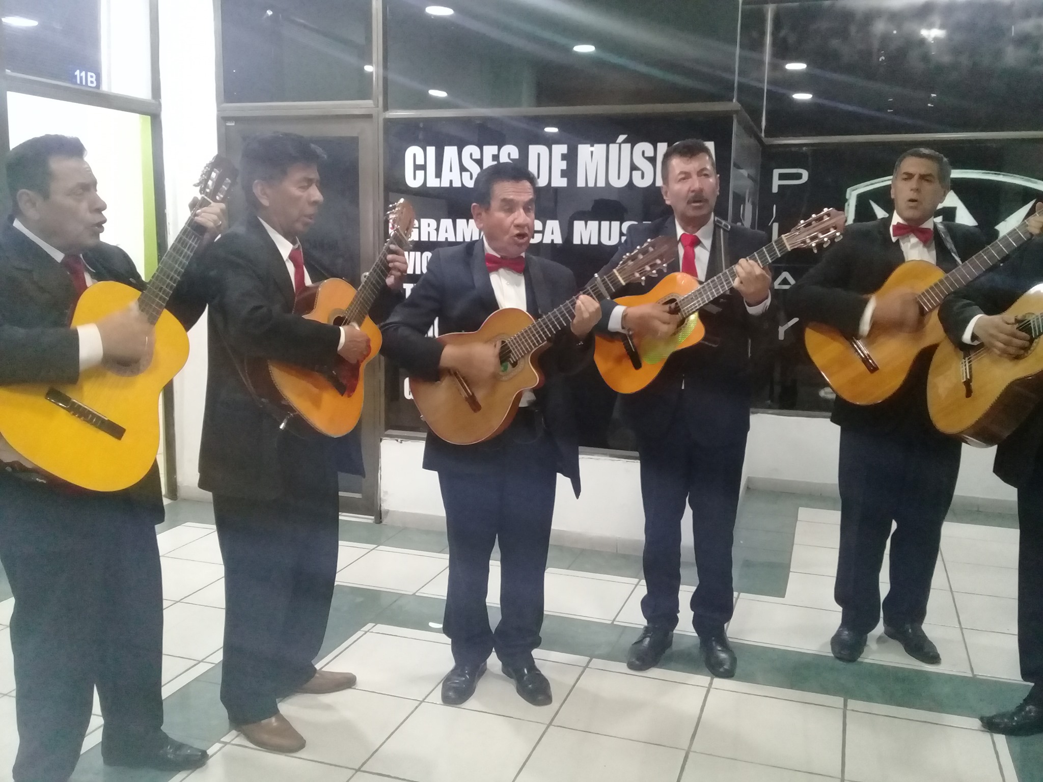 Grupo de músicos de la Playa posa cerca de un escenario al aire libre, con estructura tecnica y luces al fondo.