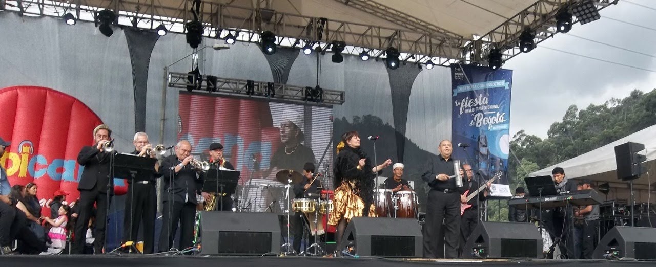 La fundadora se presenta en una tarima grande durante un evento musical al aire libre.